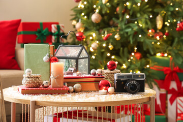 Books with Christmas balls, candles and photo camera on table in living room