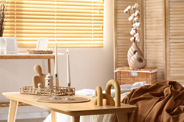 Holders with burning candles and decor on wooden table in bedroom