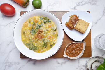 Bubur Manado or Tinutuan porridge. Indonesian food - Manado traditional rice porridge, mixed with pumpkin, corn, vegetables. Served with salted fish and sambal or chili sauce