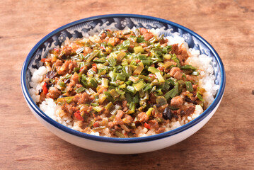 Fried minced pork with chive flower and black bean sauce over rice on wood table