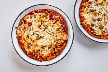 two small margherita pizzas with olives on bigger plates, portion control concept