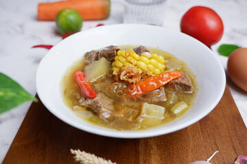 beef soup with vegetable and broth.  Asem-asem daging sapi or beef soup with sweet and sour taste, a typical dish of East Java, Indonesia.  