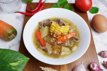 beef soup with vegetable and broth.  Asem-asem daging sapi or beef soup with sweet and sour taste, a typical dish of East Java, Indonesia.  