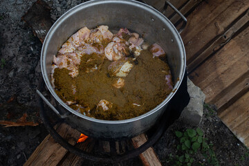 overhead view of chopped thanksgiving turkey with marinade in a large pot, a large pot of seasoned poultry being cooked using firewood