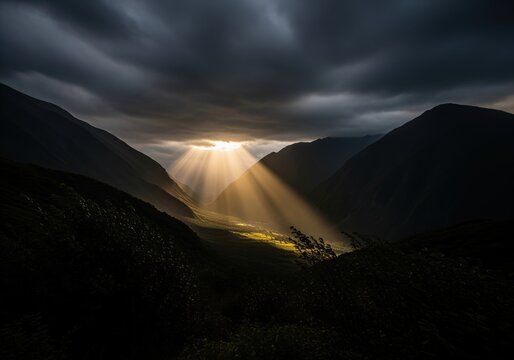 Dramatic sun rays pierce through dark stormy clouds over a majestic mountain valley