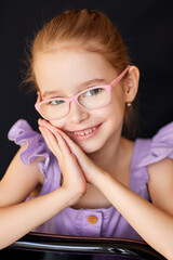 Smiling girl in pink glasses poses in soft natural light. 
Cute schoolgirl in lavender dress shows cheerful confidence.
Bright child portrait radiates innocence and intelligence.