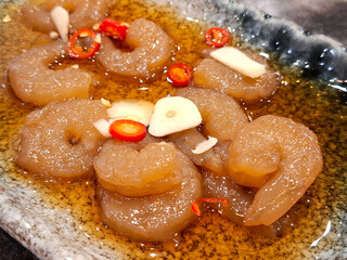 Korean Soy Sauce Marinated Raw Shrimps (Ganjang Saewoo) Appetizer, Garnished with Sliced Garlic and Red Chili Peppers in a Savory Dark Sauce