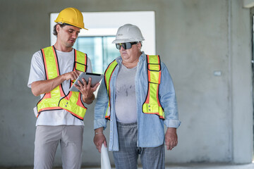 A site engineer and a foreman conduct a quality control check. The foreman uses a spirit level to verify alignment while the engineer reviews digital CAD plans on a laptop computer.