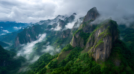 Fototapeta premium Majestic cliffs rise above green valleys in Enshi City, Hubei Province, with clouds swirling around rugged mountain peaks under a vast sky, showcasing natural beauty and dramatic landscapes.