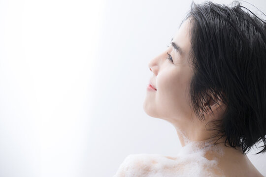 水滴が綺麗な浴室で泡で体を洗う女性のイメージ