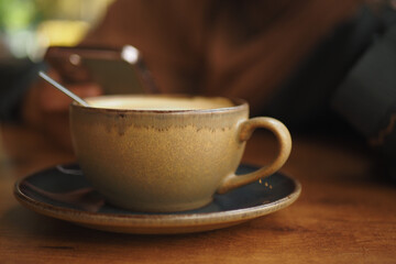 Warm coffee cup on a wooden table near a smartphone