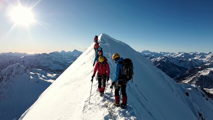 Climbing Team Ascending Snow-Capped Mountain Peak in Bright Sunlight