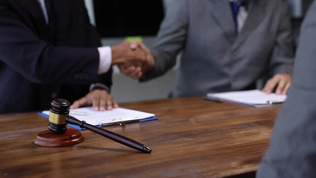 Businessman shaking hands after signing contract in a courtroom. Professional lawyers collaborating during legal consultation.