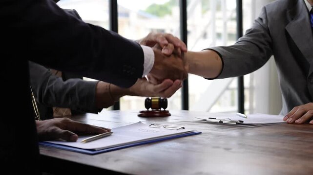 Business partnership handshake, lawyers shaking hands after signing contract in office, mediation and reconciliation to reach a compromise agreement.