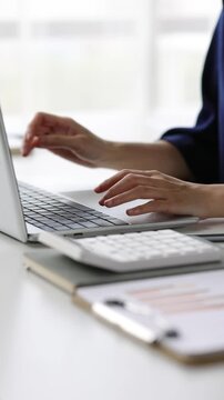 Professional female accountant analyzing financial data using laptop and calculator, carefully reviewing reports.
