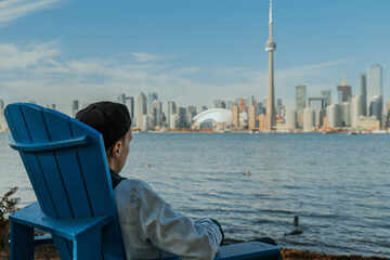 Man relaxing in a chair by the water with city skyline view on a sunny day