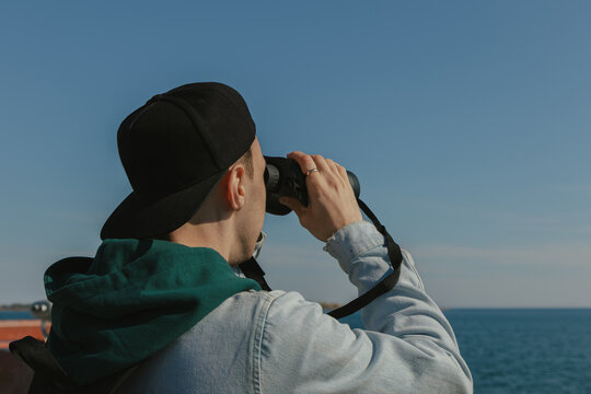 Man looking through binoculars at the sea on a sunny day