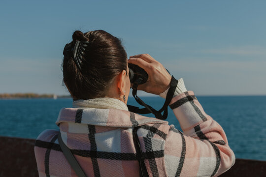 Woman looking through binoculars at the sea on a clear day
