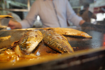 Grilled fish sizzling on the hot griddle at a market