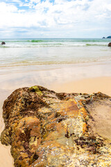 Rocky beach with rocks waves turquoise water in Patong Thailand.