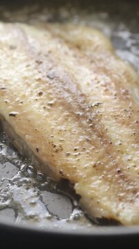 Pan-frying pangasius dory fish fillet on a hot pan. Close-up shot