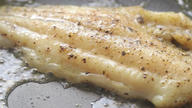 Pan-frying pangasius dory fish fillet on a hot pan. Close-up shot
