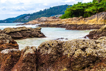 Rocky beach with rocks waves turquoise water in Patong Thailand.