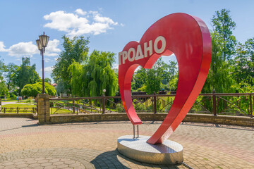 Red heart shaped GRODNO city sign in Cyrillic in park setting at Hrodna, Belarus, welcoming visitors.
