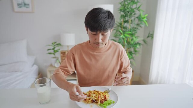 Asian handsome young man eating spaghetti and dimsum in kitchen at home.