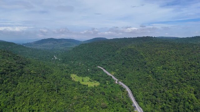 Drone footage of the aerial view of a winding road cutting through lush green forest. Scenic highway number 304 in Thailand links the Bangkok area to Nakhon Ratchasima in the northeastern region