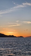 Stunning sunset reflecting on the tranquil ocean with distant islands creating a peaceful tropical vibe, perfect for travel blogs or serene backgrounds