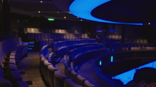 Cinema auditorium defocused with curved blue ceiling and rows of seats interior; backplate copyspace template calm.