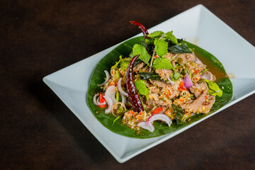 A vibrant and delicious Thai dish, beautifully presented on a leaf and plate, is ready to eat