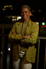 Confident smiling woman with arms crossed at night