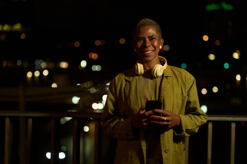 Young woman smiling using smartphone at night city