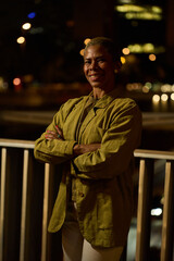 Woman smiling with arms crossed in urban night