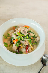 A delicious bowl of soup with vegetables and herbs, ready to be enjoyed. The soup is presented in a white bowl with a spoon