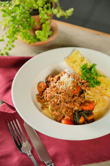 Delicious pasta dish with meat sauce and tomatoes, captured in a restaurant setting. The plate is garnished with parsley
