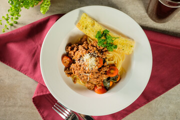 Delicious Spaghetti with Meat Sauce and Garlic Bread. The dish is a culinary delight, with a generous serving of spaghetti, flavorful meat sauce, fresh tomatoes, and grated cheese.
