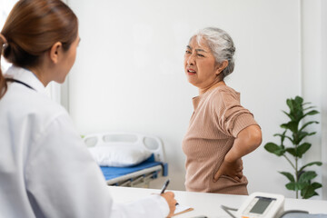 Fototapeta premium Elderly patient experiencing lower back ache at doctor office, physician taking notes, discussing health problem during examination