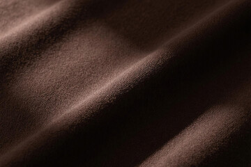 Fototapeta premium Deep brown fabric background with subtle texture and soft lighting from upper left, creating natural gradients and gentle shadows for an elegant atmosphere.