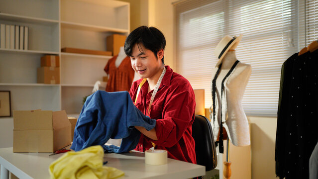 A focused male tailor examines blue fabric in a well-equipped studio with sewing tools, showcasing precision and skill. online clothing store