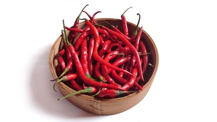 Top view of Red chili peppers or Cabai Merah Keriting on bamboo bowl. Isolated on white background with copy space. Perfect for design element, spicy food concept or any commercial usage.