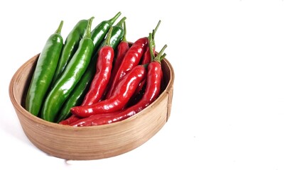 Side view of Two varians hot chili peppers on bamboo bowl.  Red and green chili pepper isolate on white background with copy space. Perfect for design element, spicy food concept. 