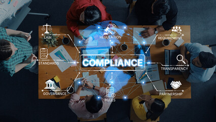 A diverse team engages in a collaborative meeting focused on compliance and regulation in a modern office, illustrating active discussions and strategic planning. Trope