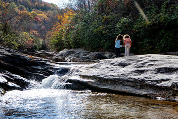 Obraz premium Children playing near a waterfall on the Blueridge mountain parkway near Asheville North Carolina in peak Fall colors