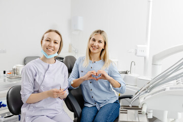 Dentist and patient making heart shape with hands in dental clinic