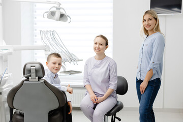 Dentist explaining dental hygiene to mother and child in clinic