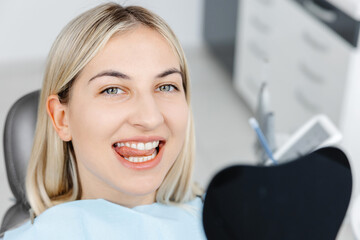 Smiling patient sitting in dentist chair showing perfect teeth