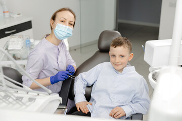 Happy dentist and child patient showing thumbs up in dental clinic